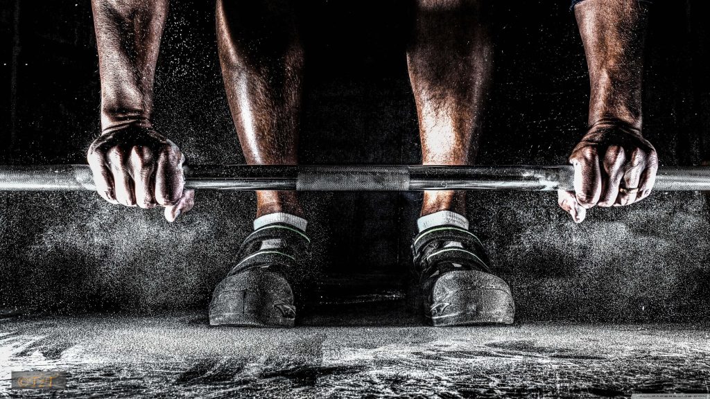 Close-up of athlete lifting heavy barbell with chalk dust explosion on dark gym background Wallpaper