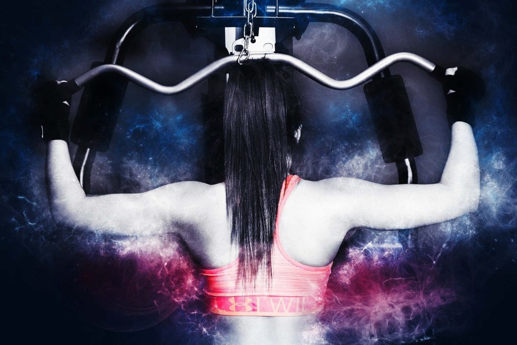 Woman doing lat pulldown workout in Under Armour sports bra with blue purple smoke background Wallpaper