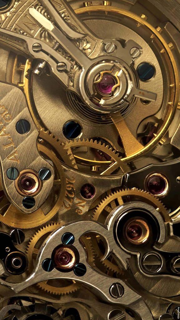 Closeup of A Lange Söhne watch mechanism golden gears blued screws and ruby jewels wallpaper