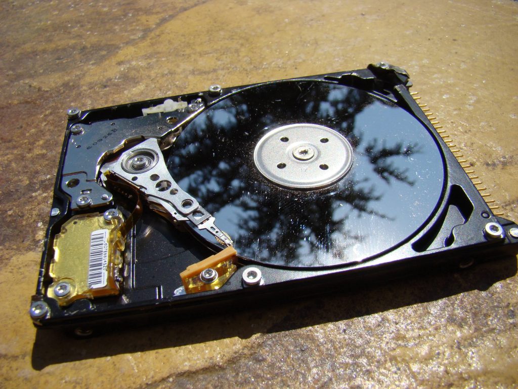 Intricate black computer hard drive on stone surface with sunlight highlighting internal components Wallpaper