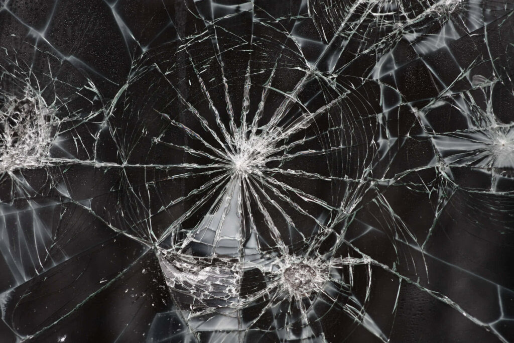 Broken glass wallpaper with detailed sharp cracks and geometric shattered fragments on dark background