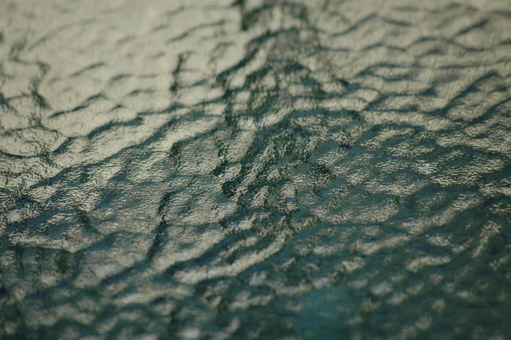 Close-Up Cracked Glass Wallpaper with Wavy Greenish Patterns