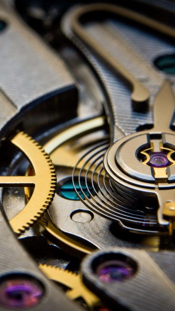 Closeup of intricate gold gears silver bridges and purple rubies in luxury mechanical watch movement Wallpaper
