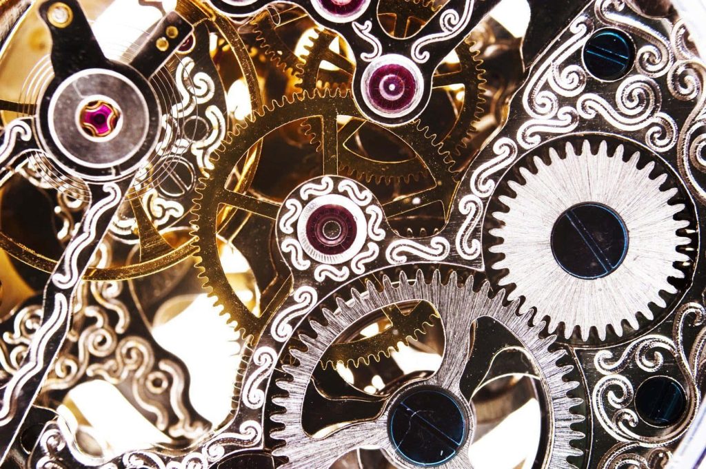 Closeup of ornate golden silver watch gears and red jewels detailed skeletonized movement wallpaper