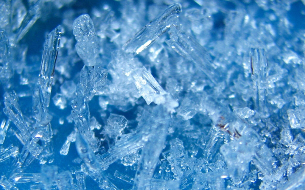 Close-up of intricate blue and white ice crystals with geometric patterns for frosty wallpaper background