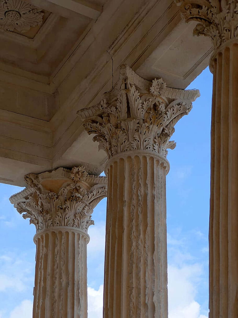 Intricate Maison Carrée Columns Wallpaper Against Blue Sky