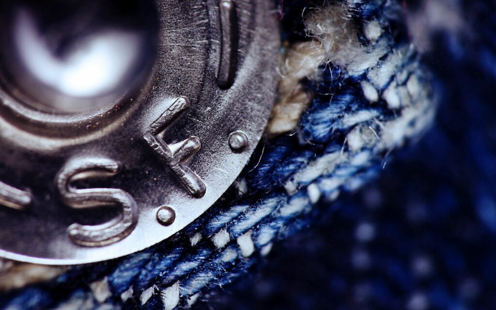 Close-Up Metallic Button on Textured Fabric Wallpaper Background