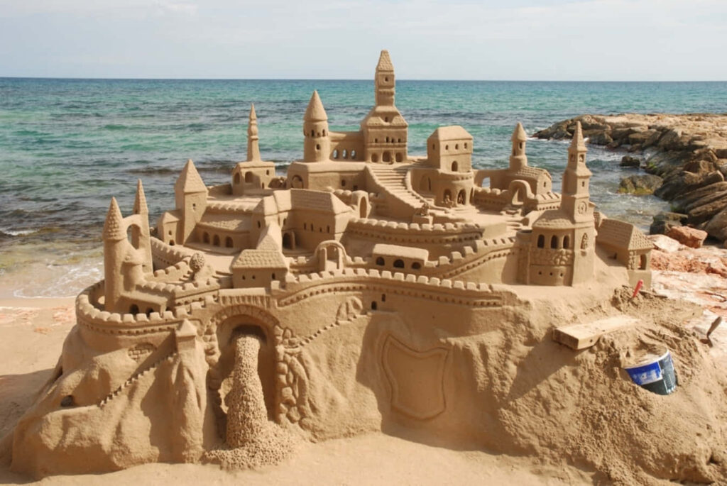 Intricately Crafted Sandcastle Beach Wallpaper with Ocean Background