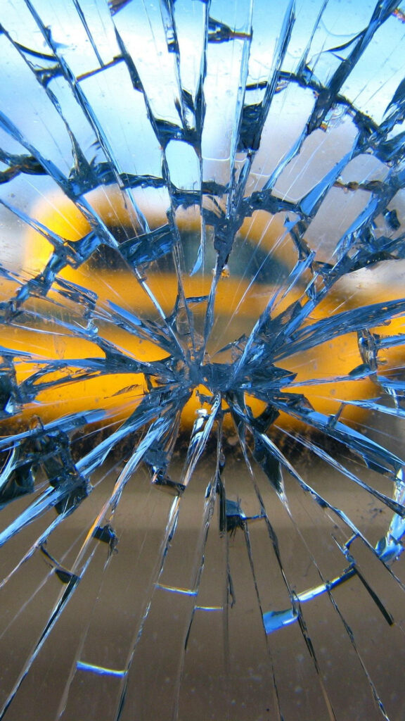 Close-up of shattered glass wallpaper with intricate blue and amber cracks for edgy background