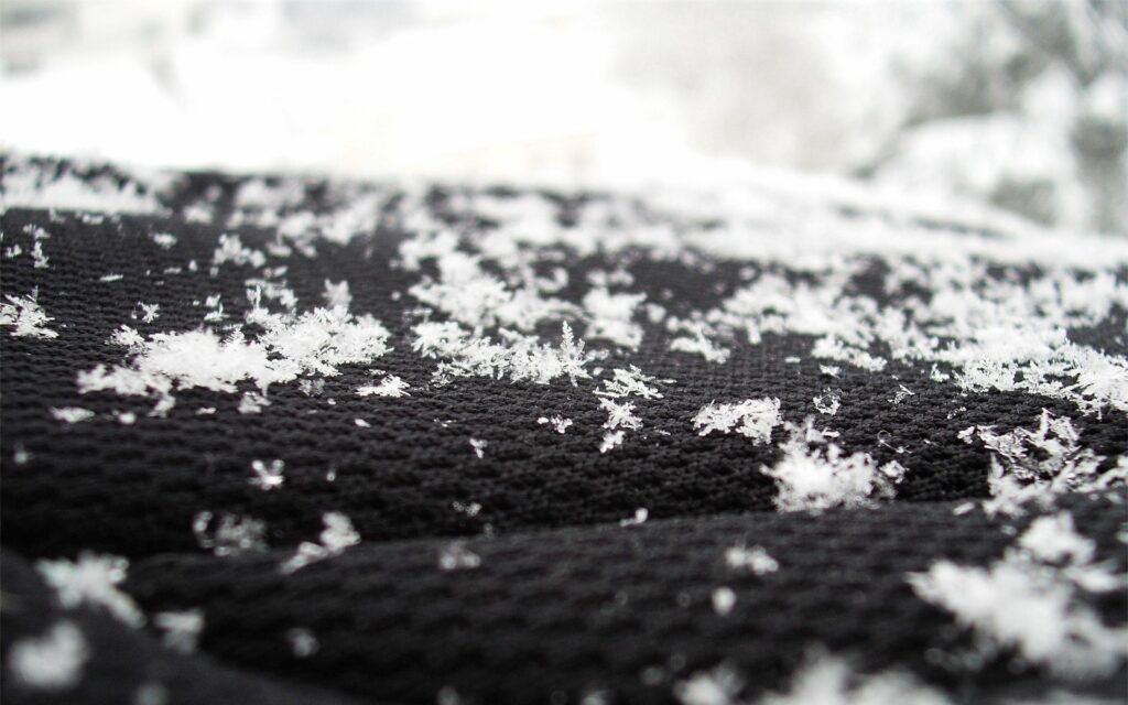 Intricate White Snowflakes on Textured Black Surface Wallpaper