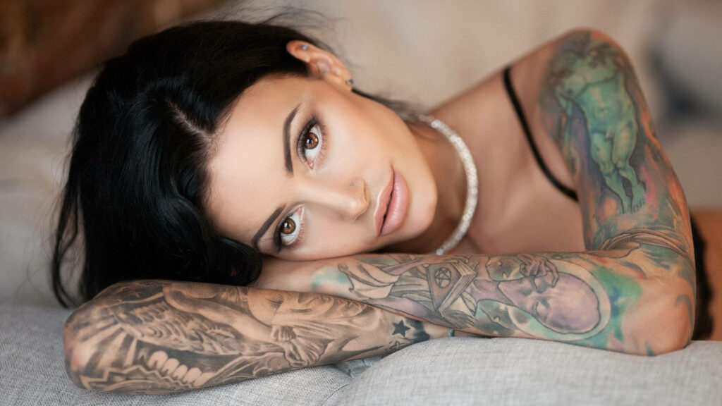 Inked Elegance: Stunning Arm Tattoo Wallpaper featuring a Beautifully Inked Girl and Aged Alien Design