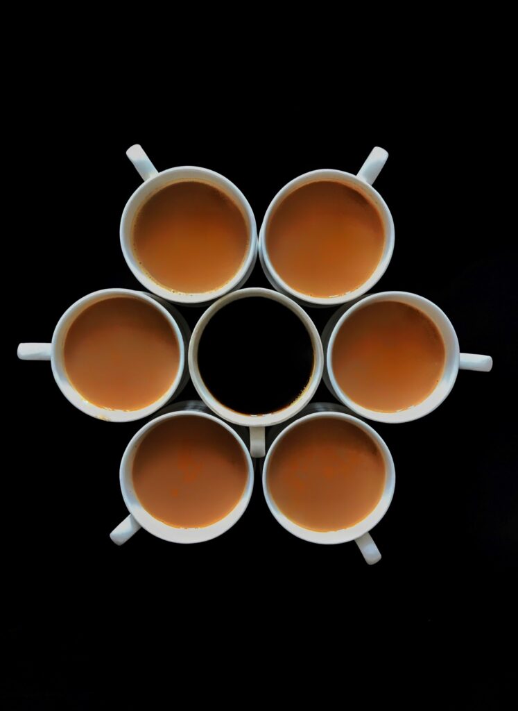 Symmetrical Masala Tea Cups Wallpaper: Warm Tones on Black Background