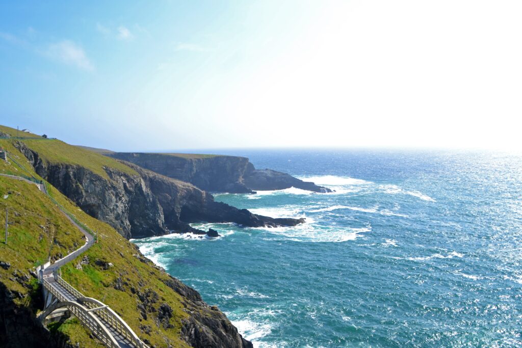Ireland coastline wallpaper with dramatic cliffs emerald hills and waves crashing on beach