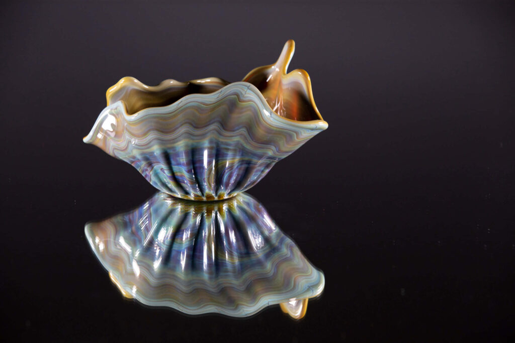 Elegant pastel clam shell with iridescent waves reflecting on glossy dark ocean-inspired wallpaper