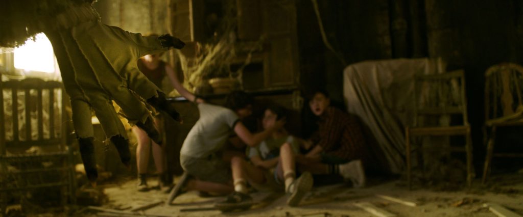 Children huddled in dark room scared as Pennywise clown's clawed hand reaches in horror wallpaper