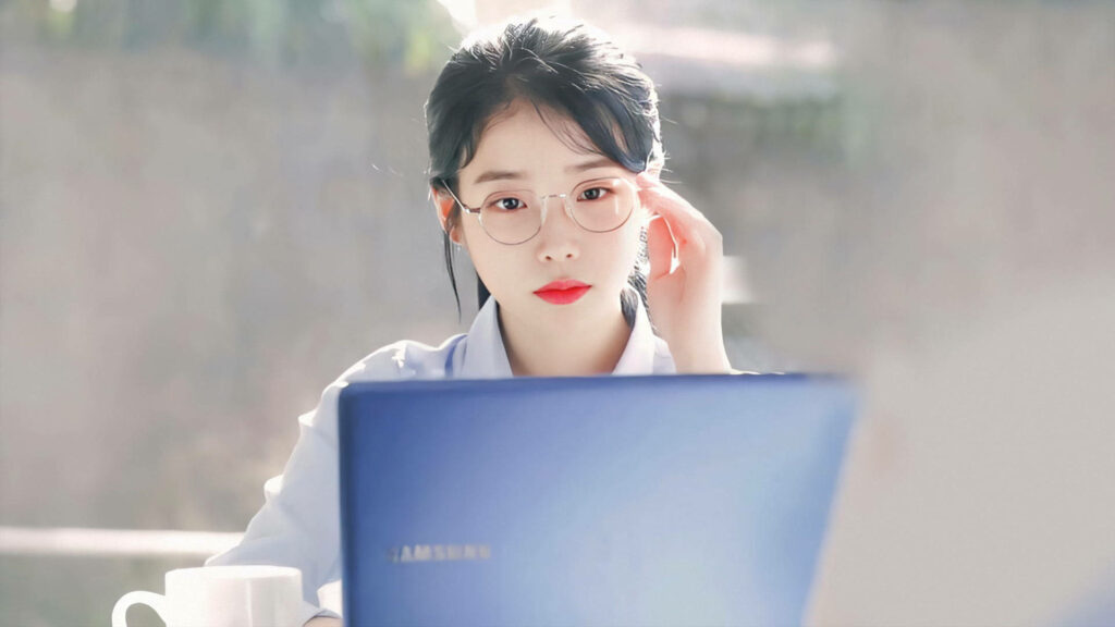 Chic and Focused: IU in Transparent Eyeglasses While Working on Her Laptop Wallpaper