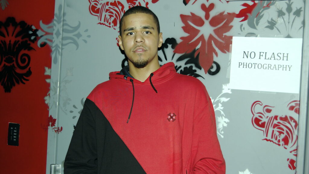 J Cole Captivates with Intense Stare Through Glass, Red Black T-shirt Adds Edgy Vibe: QHD Music Wallpaper