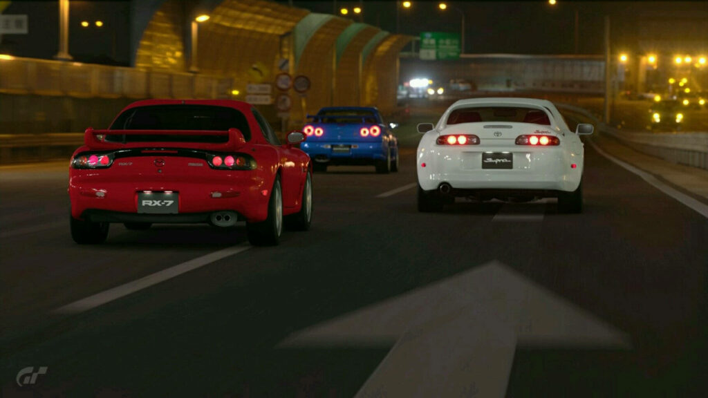 Three iconic JDM cars Mazda RX-7 Nissan Skyline Toyota Supra racing on city highway at night Wallpaper