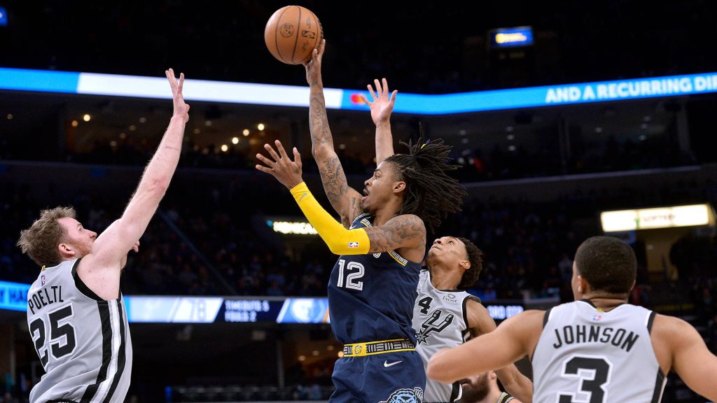 Ja Morant leaps for contested layup against Spurs defenders in vibrant NBA game action Wallpaper