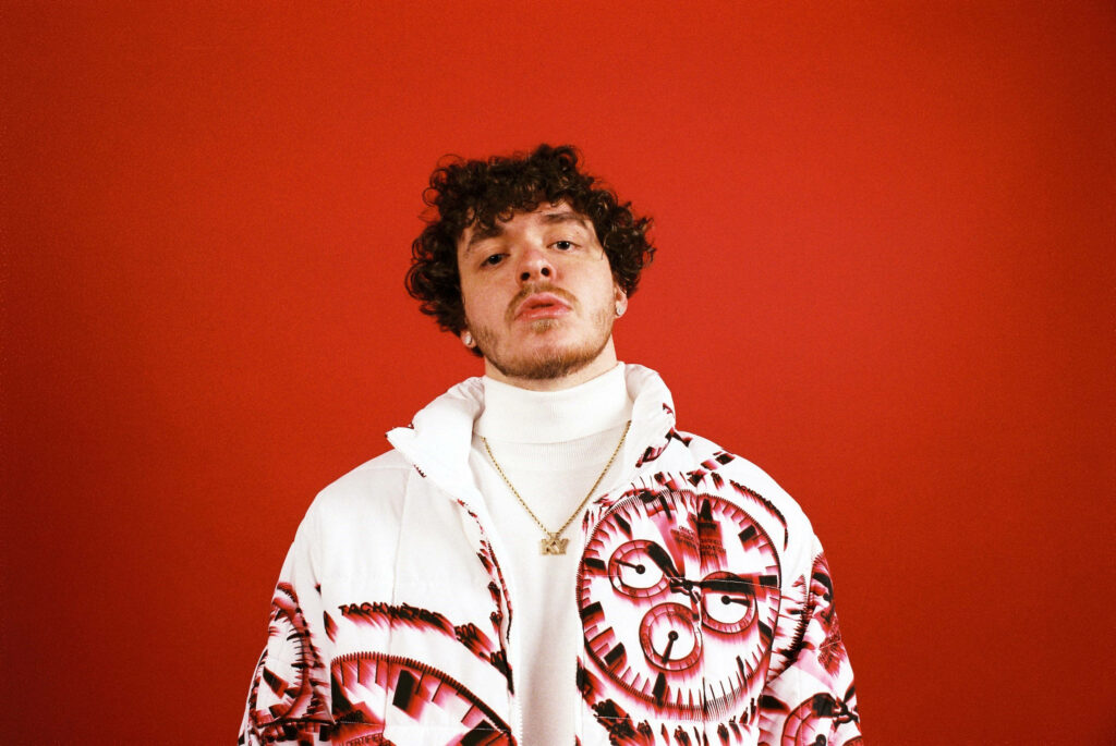 Jack Harlow's Bold Supreme Jacket Wallpaper on Red Background
