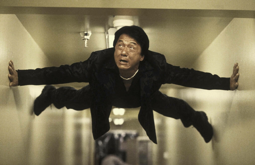 Jackie Chan performing daring action stunt in narrow hallway Rush Hour 2 dynamic wallpaper