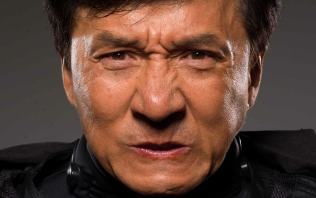 Close-up of Jackie Chan with intense determined expression powerful presence wallpaper background