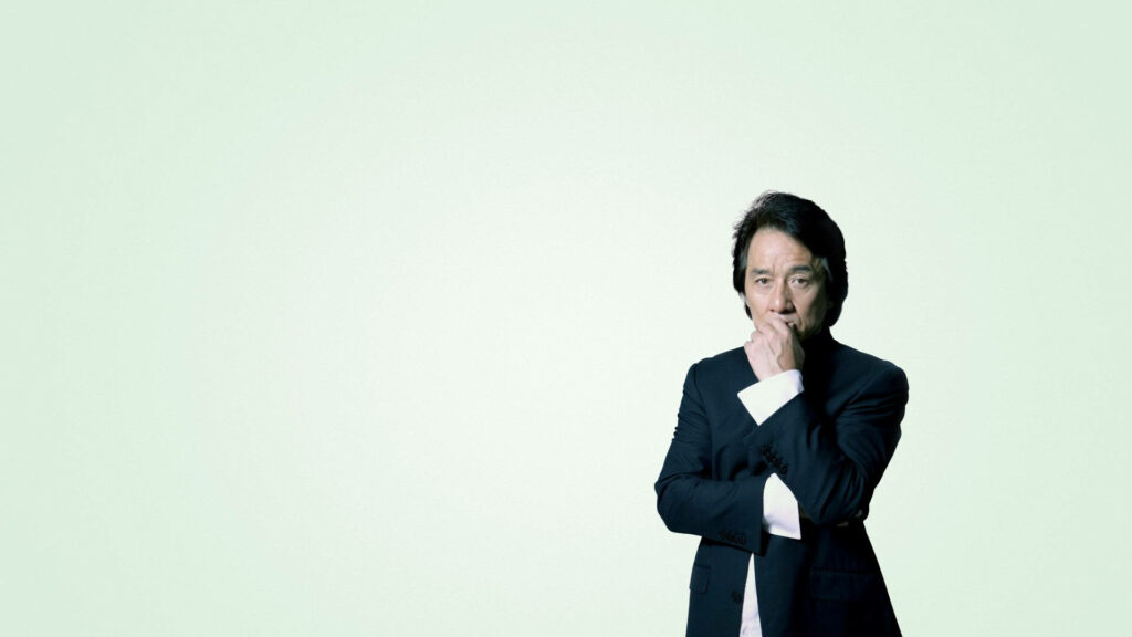 Jackie Chan thoughtful pose against pale minimalist background reflecting deep insight wallpaper
