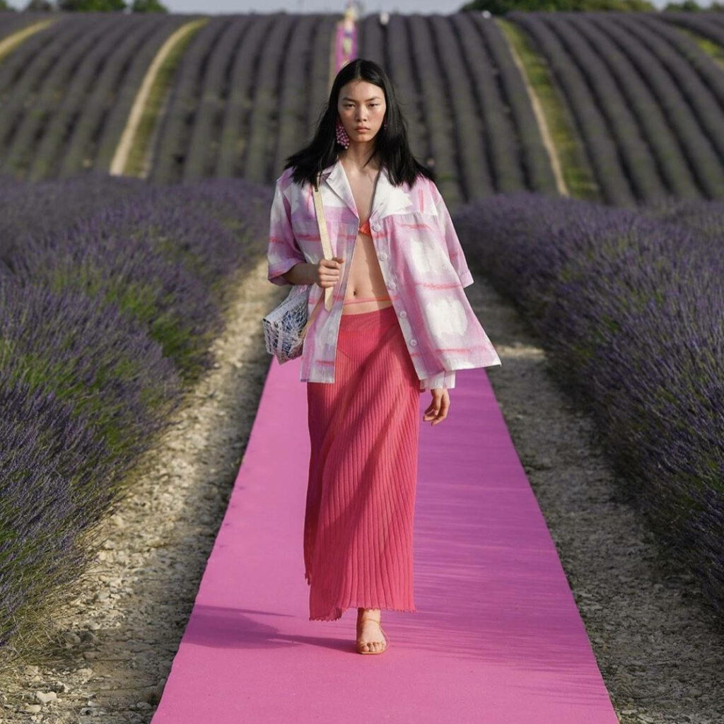 Jacquemus model on vibrant pink runway surrounded by blooming lavender fields fashion contrast Wallpaper