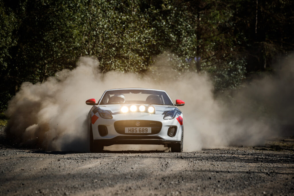 Jaguar F-Type: Thrilling Sports Car Racing Through Lush Greenery Wallpaper