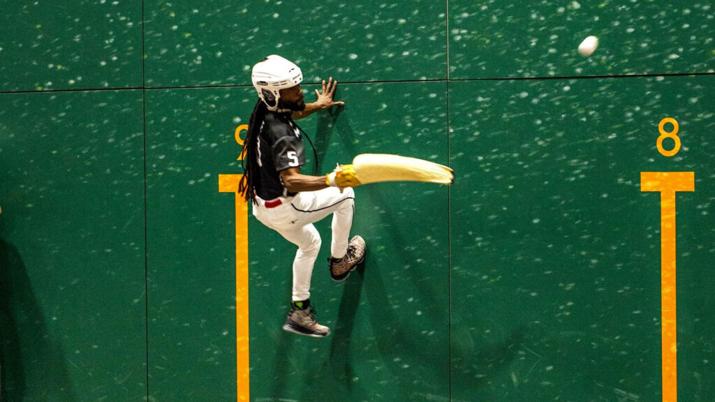 Dynamic Jai Alai Player Wallpaper: Action on a Green Court Background