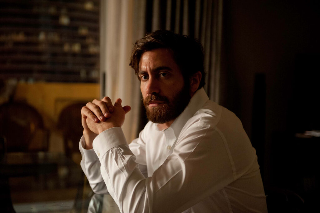 Jake Gyllenhaal intense agitated look white shirt seated table softly lit room wallpaper background