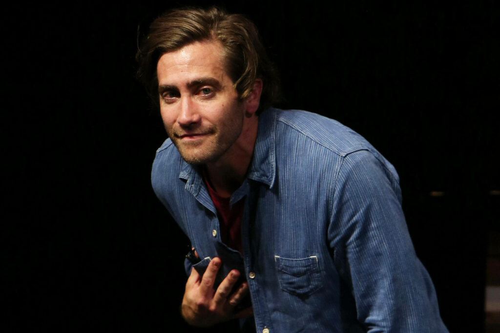 Jake Gyllenhaal in blue shirt relaxed pose dark background stylish wallpaper image