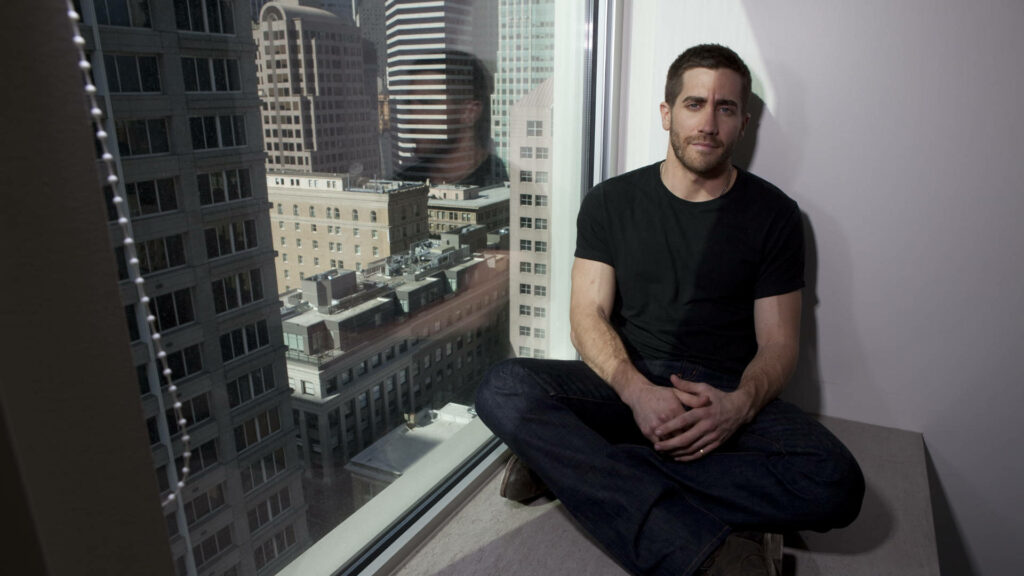 Jake Gyllenhaal relaxed by large window cityscape natural light contemplative wallpaper background