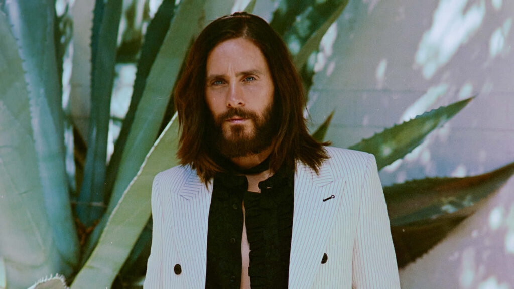 Jared Leto Close-Up: Stylish Look Amidst Lush Green Plants Wallpaper