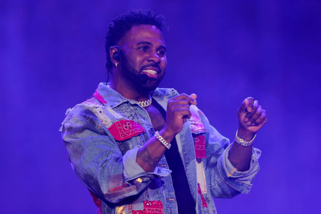 Jason Derulo performing energetically on stage in denim jacket at MDLBEAST vibrant purple background Wallpaper