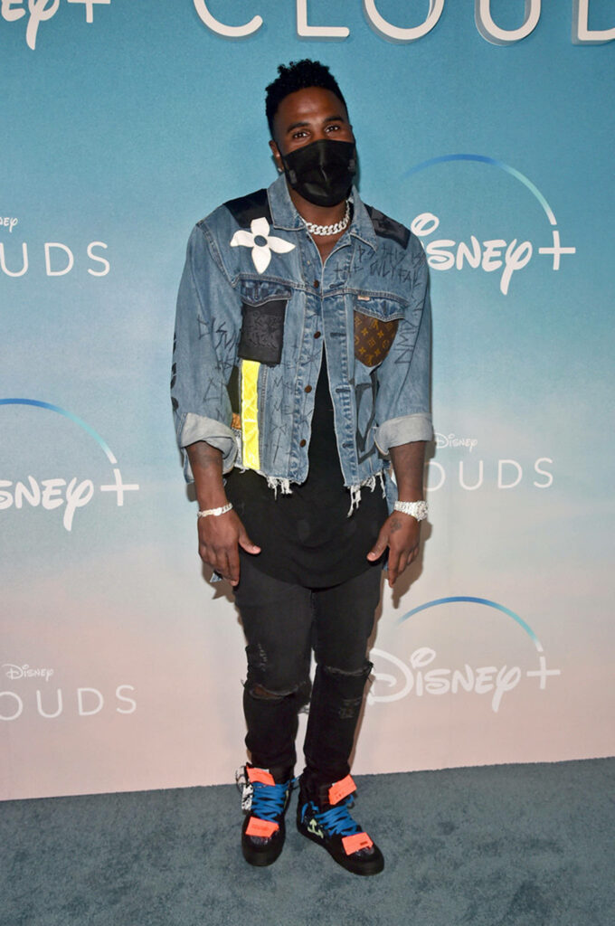 Jason Derulo stylish in denim jacket black jeans colorful sneakers Disney clouds backdrop Wallpaper