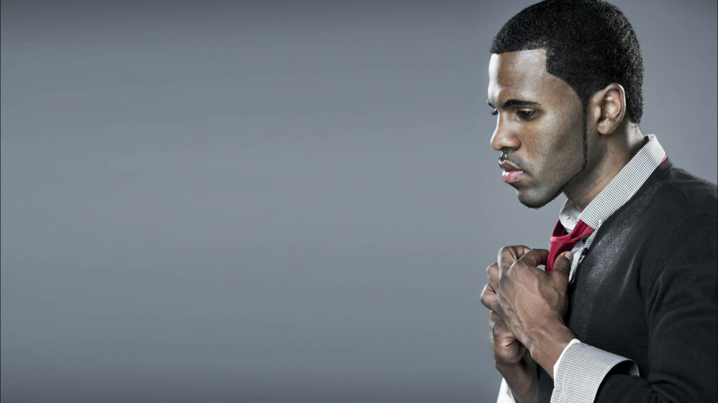 Jason Derulo styling red tie in modern fashion photo against soft gray background wallpaper
