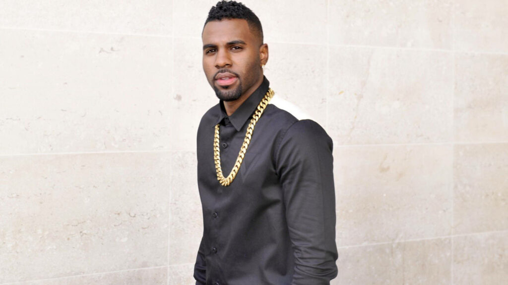 Jason Derulo in black shirt with bold gold chain against light stone wall stylish wallpaper background