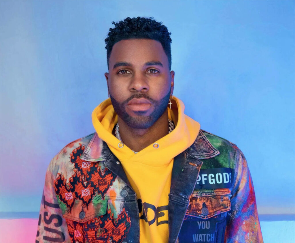 Jason Derulo in colorful printed jacket and yellow hoodie vibrant blue pink background wallpaper