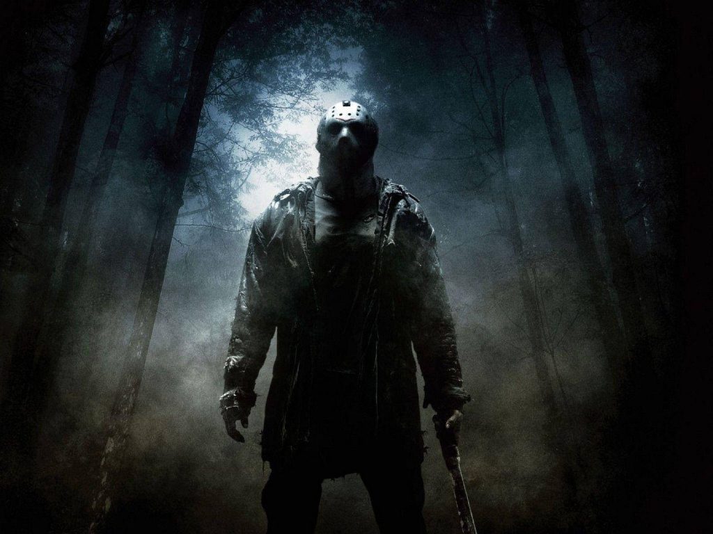 Jason Voorhees in dark forest with hockey mask and machete under eerie moonlight wallpaper