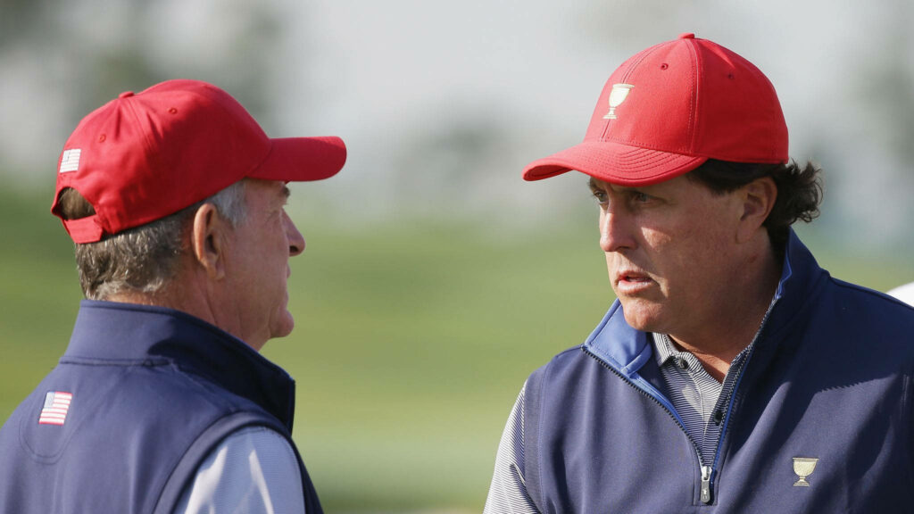Jay Haas and Bill Haas in red caps discussing strategy on golf course teamwork wallpaper background