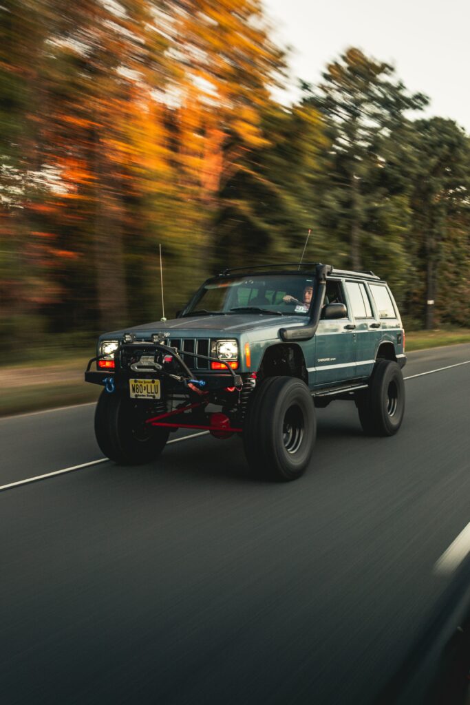 Jeep Cherokee in Motion: Off-Road Power Against Blurred Trees Wallpaper