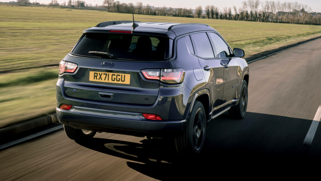 Jeep Compass driving on smooth road beside open grassy fields scenic adventurous background Wallpaper