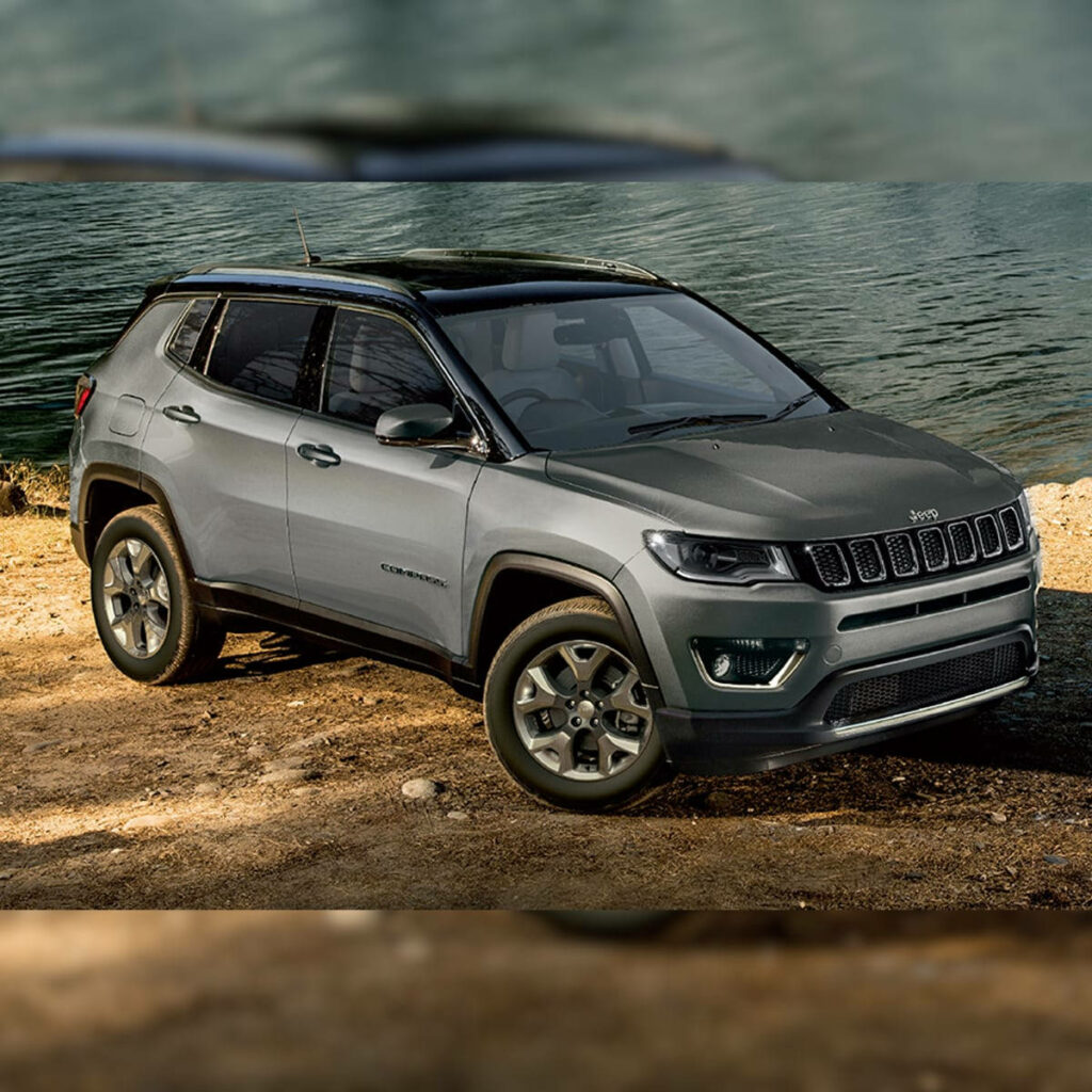 Rugged Jeep Compass parked on dirt trail beside calm water showcasing off-road adventure spirit Wallpaper