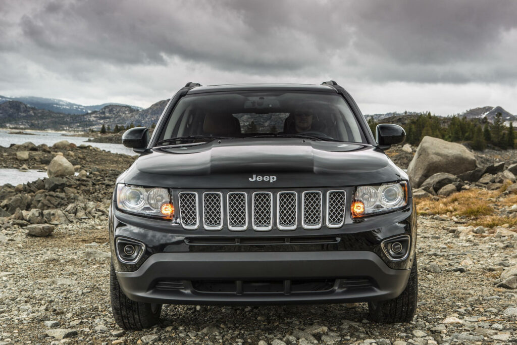 Jeep Compass on rocky terrain under cloudy sky showcasing rugged off-road adventure spirit Wallpaper
