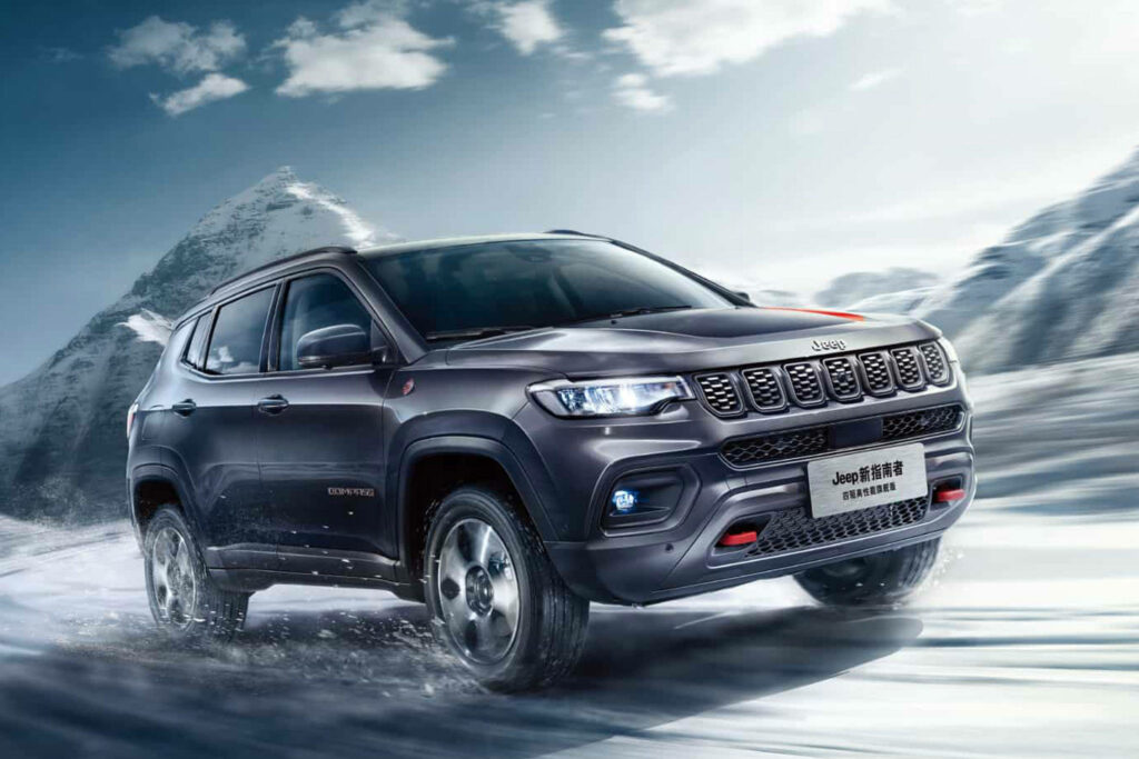 Jeep Compass driving across snowy terrain with majestic mountains in background adventure wallpaper