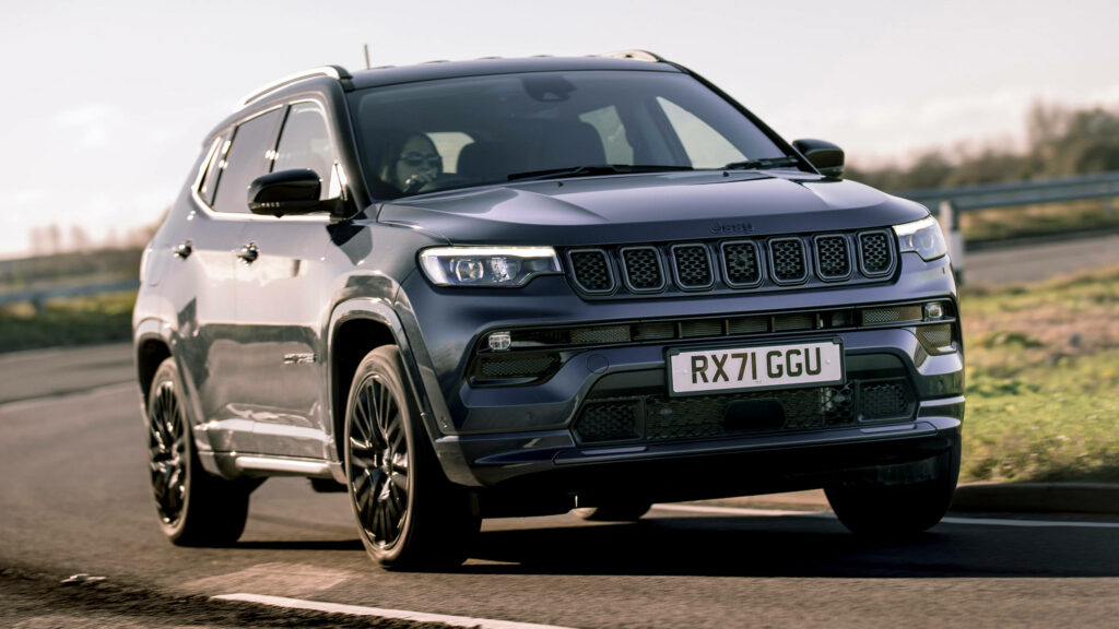 Sleek Jeep Compass driving curved road showcasing bold design dynamic performance daylight Wallpaper