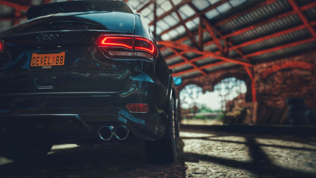 Jeep Trackhawk parked in rustic barn sunlit highlighting sleek black exterior and tail lights Wallpaper