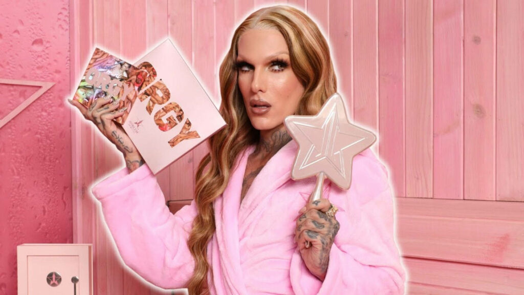 Jeffree Star in pink robe holding Orgy eyeshadow palette and star mirror pink themed background Wallpaper
