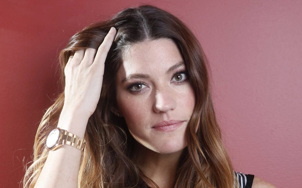 Jennifer Carpenter elegant portrait wavy brown hair soft lighting muted red backdrop gold watch Wallpaper